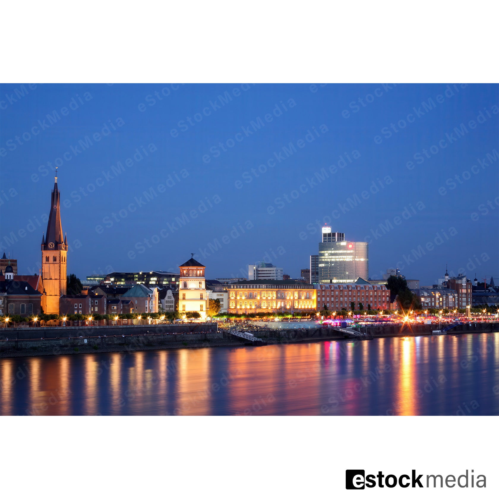 Düsseldorf waterfront at night with colorful reflections on the Rhine River.