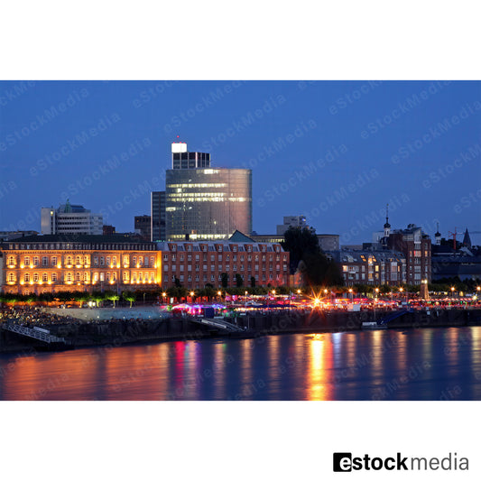 Düsseldorf waterfront at night with colorful reflections on the Rhine River.