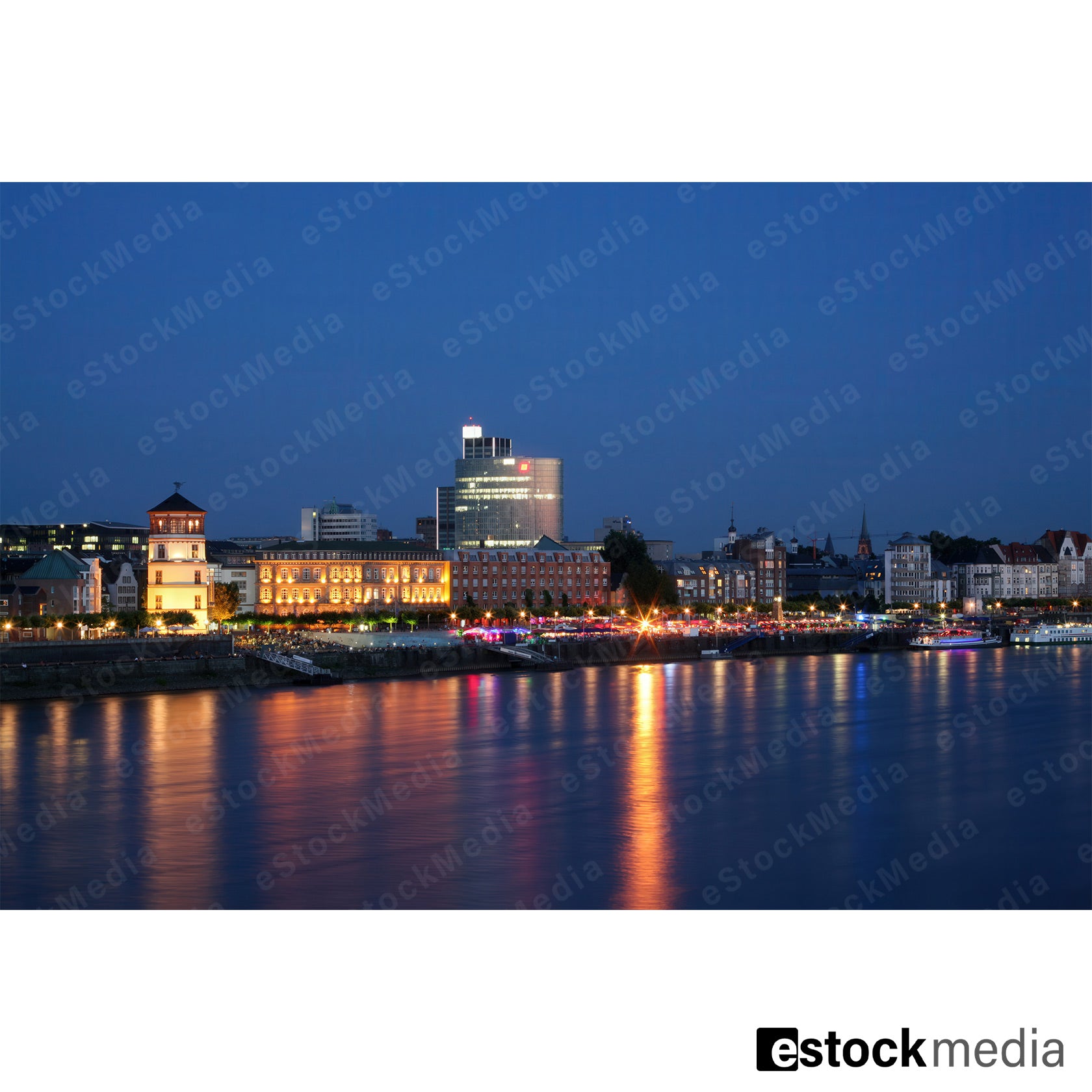 Cityscape of Düsseldorf illuminated at dusk with reflections on the Rhine.