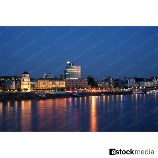 Cityscape of Düsseldorf illuminated at dusk with reflections on the Rhine.