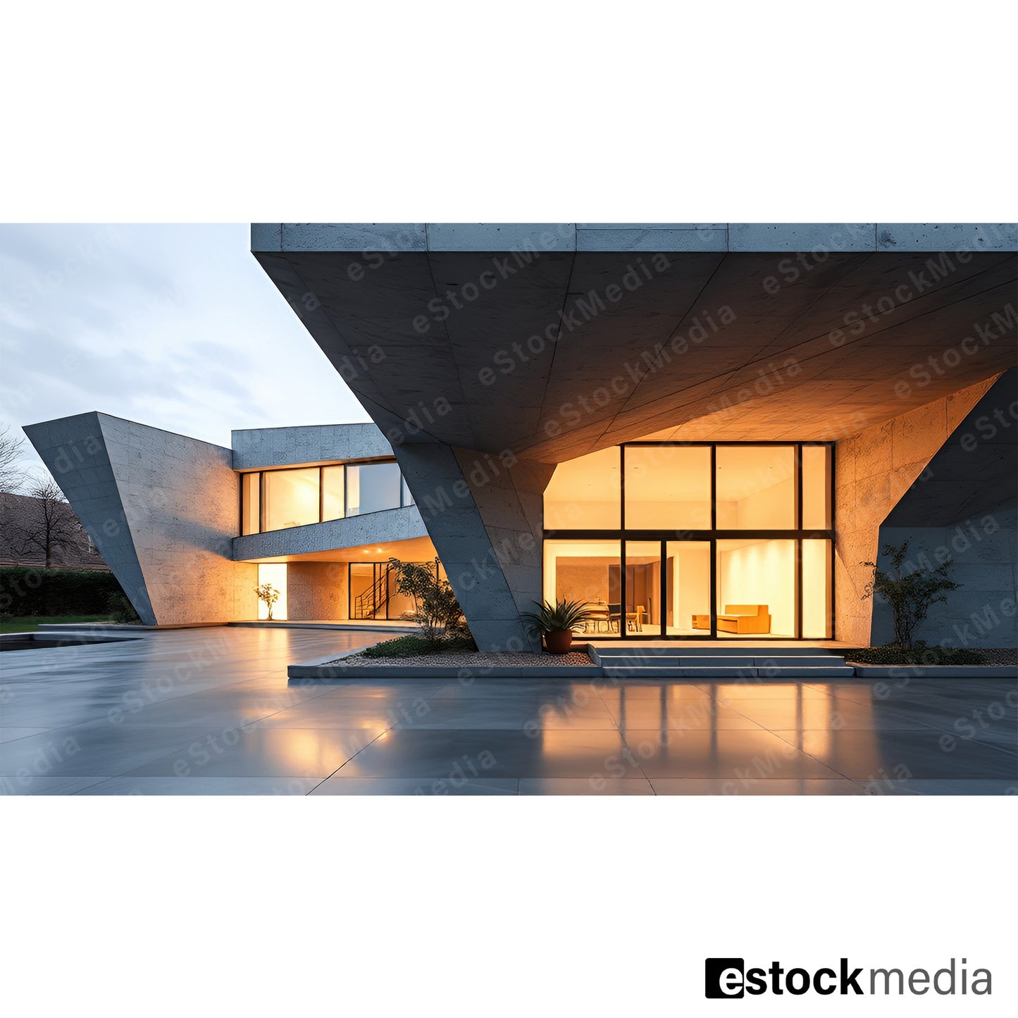 A modern concrete residence with bold geometric shapes and large glass windows, displaying warm interior lighting and a reflective patio surface.