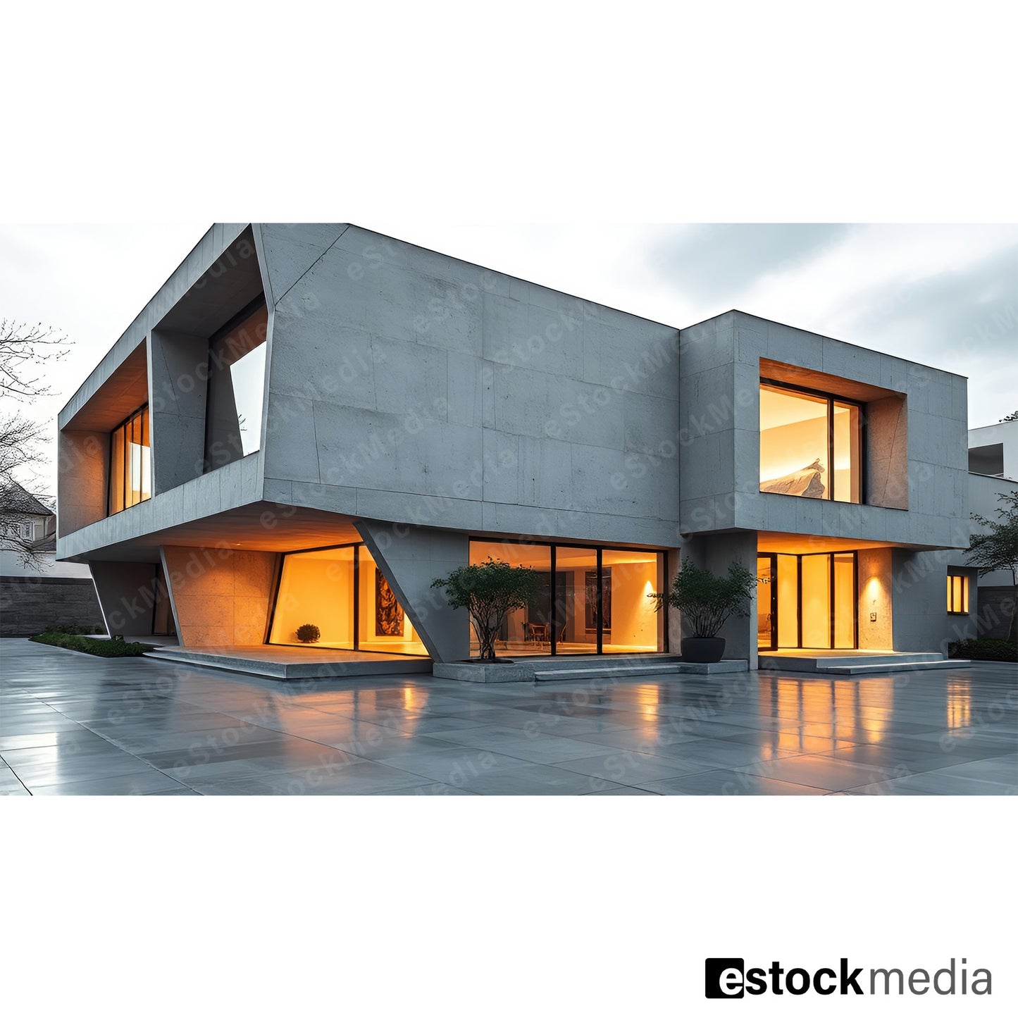 Modern concrete building with geometric design and large glass windows featuring warm interior lighting